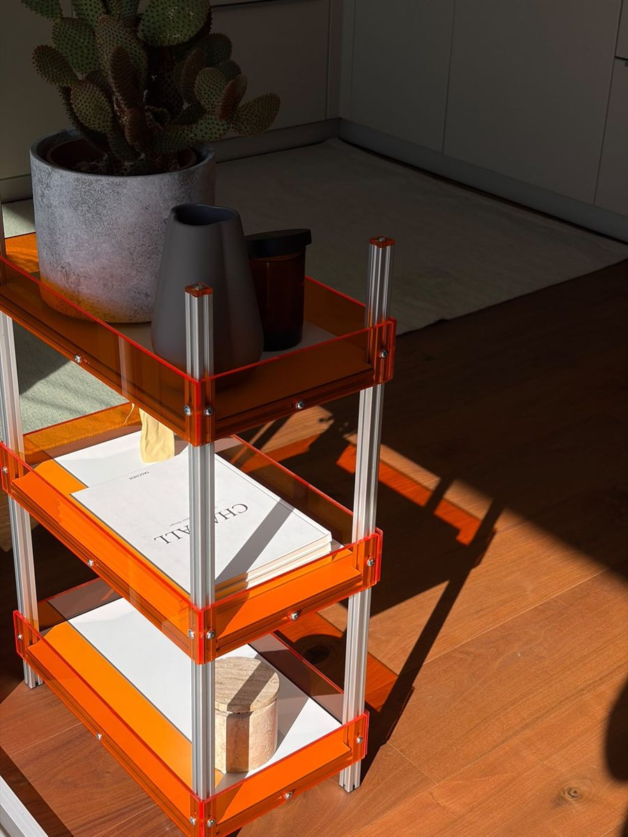 Regal im Sonnenlicht, das orangefarbene Schatten auf den Holzboden wirft